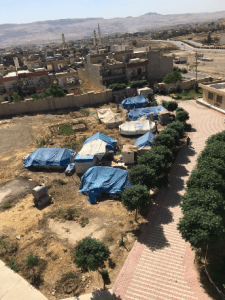 [Image description: photograph of several tents pitched in an empty lot.